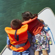 children-looking-down-into-sea-water-on-boat
